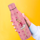 una persona sosteniendo una botella rosa con una imagen de una bailarina en ella