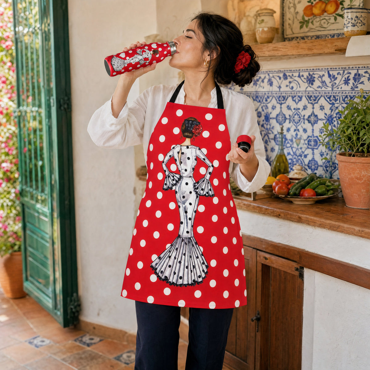 Mujer con delantal flamenco María Blanco bebiendo de la botella térmica en la cocina