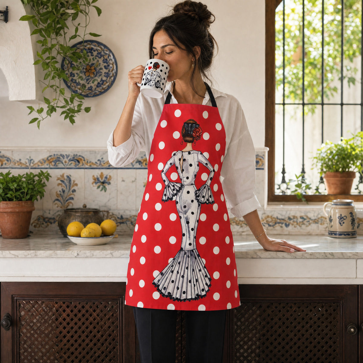 Mujer con delantal flamenco María Blanco tomando café en la taza a juego