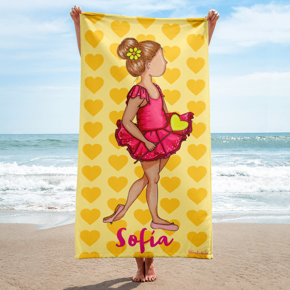 a young girl holding up a yellow beach towel with a picture of a little girl