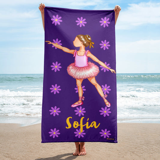 a little girl holding a purple towel with a picture of a ballerina on it