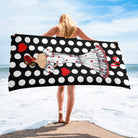 a woman standing on the beach holding a polka dot towel