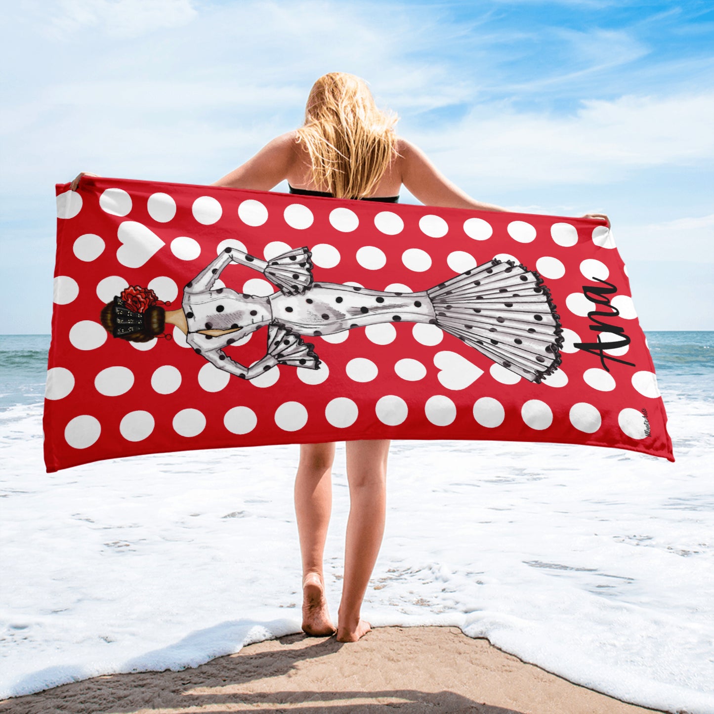 a woman standing on a beach holding a polka dot towel